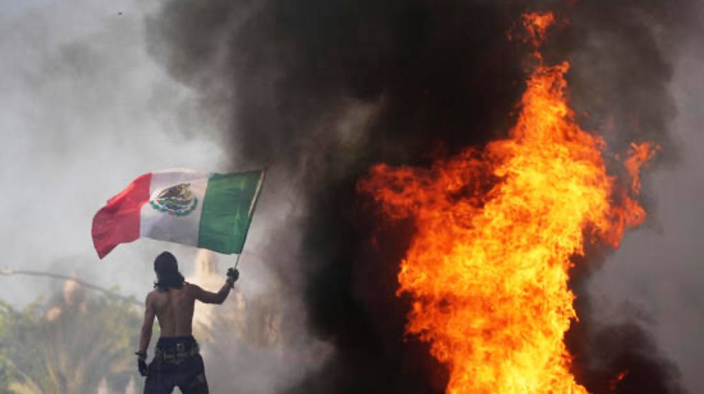 Burning cars and protesters clash with police during LA riots after ICE raids.